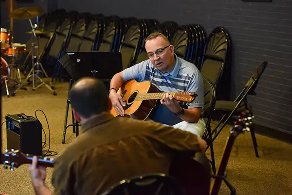 A man learns guitar in a private lesson.