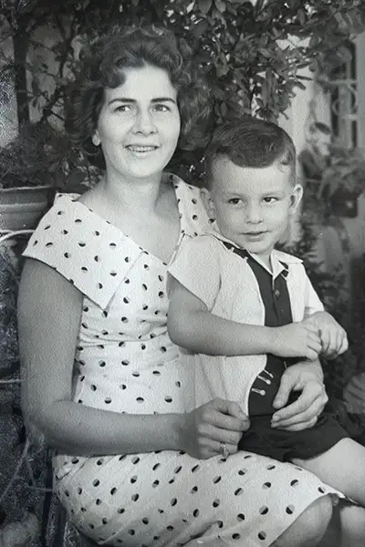A young boy sits on a woman’s lap in a black-and-white vintage photo.