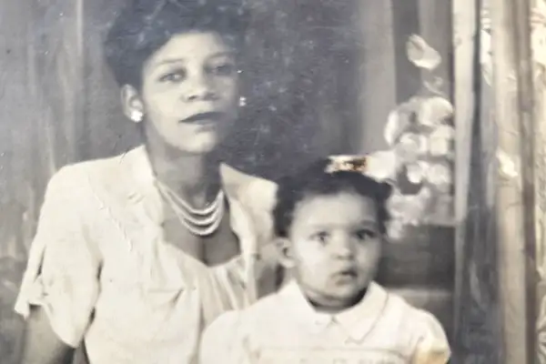 A toddler sits on the lap of an African American woman in a vintage photograph