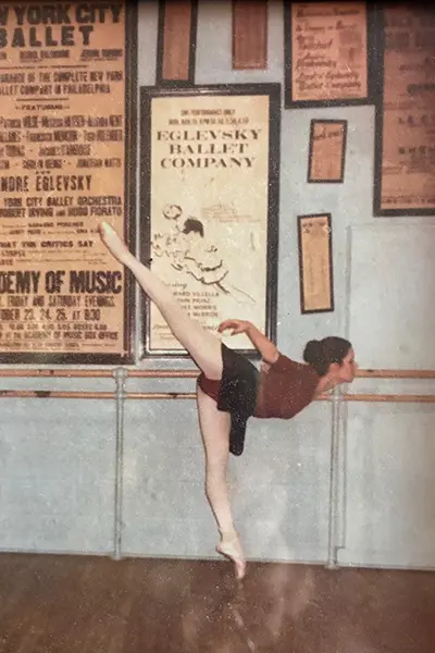 A dancer wearing pointe shoes stands with one leg extended.