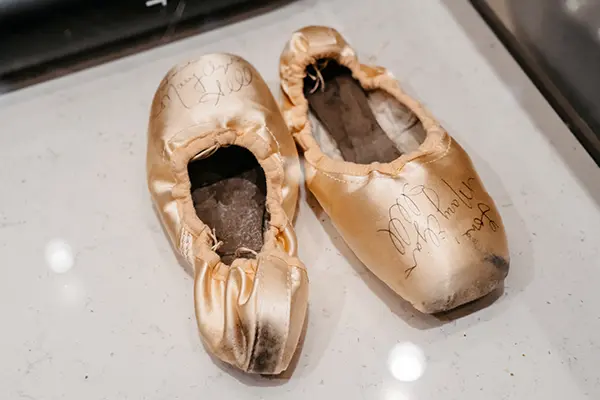 Ballet shoes with signatures written on them.