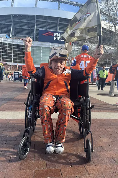 A man raises his fist in celebration outside of a football stadium.