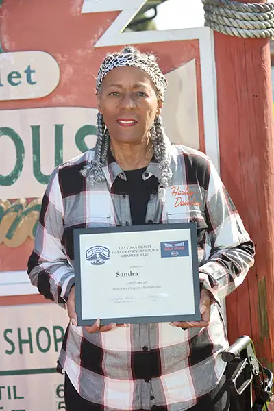 An older African American woman holds an award.