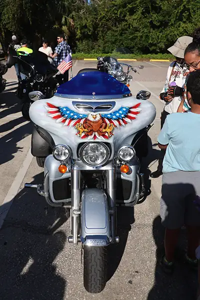 People stand around a motorcycle with an eagle painted on it.