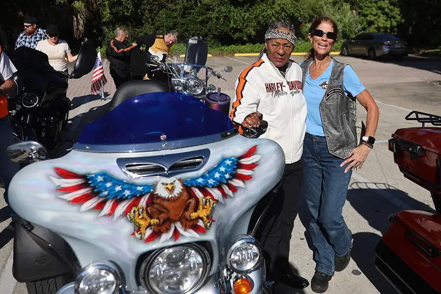 Two women in Harley-Davidson gear stand next to a motorcycle.