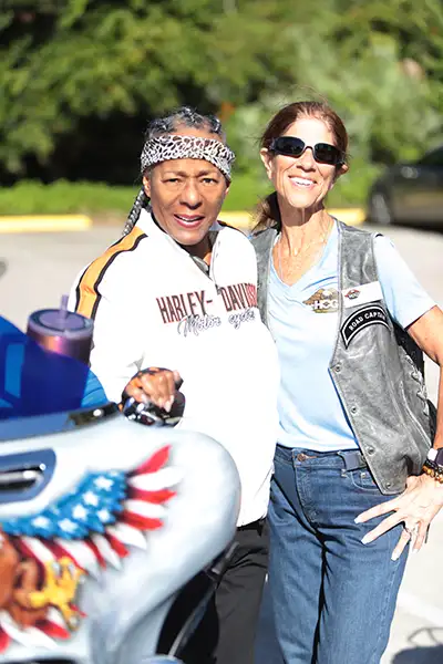 Two women stand beside a Harley-Davidson motorcycle.