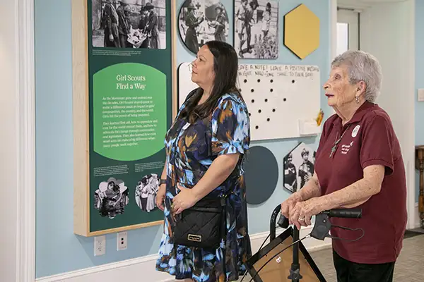 An older and younger woman read information on the wall of a museum.