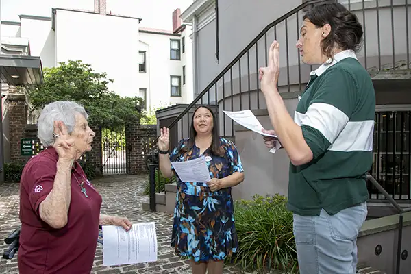 Three people recite a pledge with fingers raised.