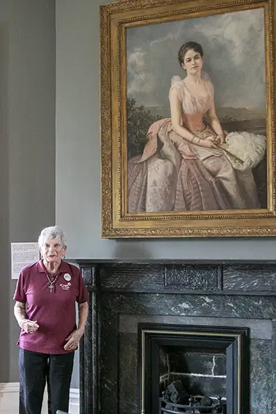 A woman stands next to an early 1900s portrait of a woman.