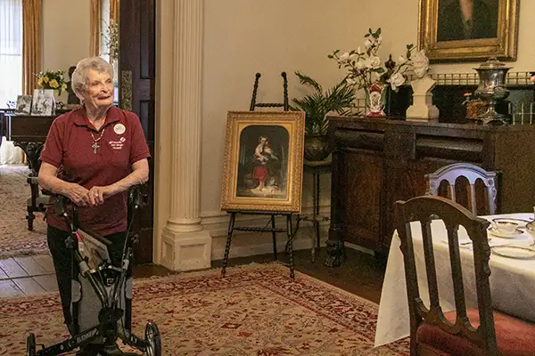 An older woman stands in the dining room of a historic home.
