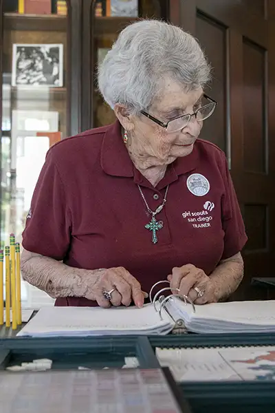 A woman reads from pages in a binder.