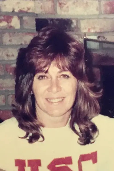 A woman smiles in front of a brick fireplace.