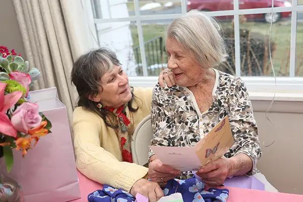 Two women look at a greeting card together.