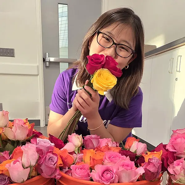 A young woman holds a bouquet of roses in front of her face