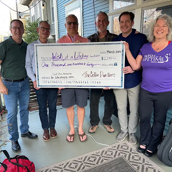 A group of people hold up a big donation check