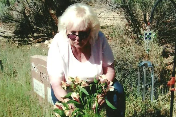 A woman places flowers on a grave