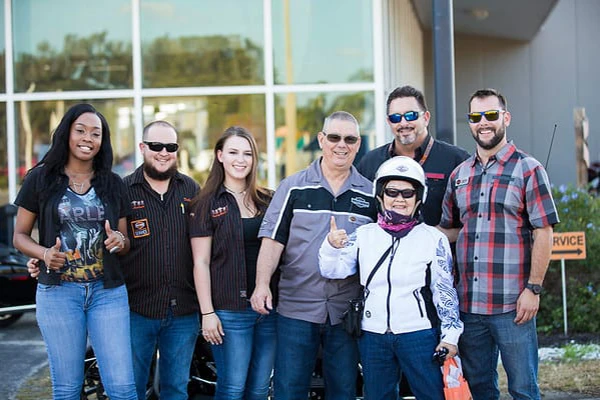 A woman in full motorcycle riding gear with a group of people
