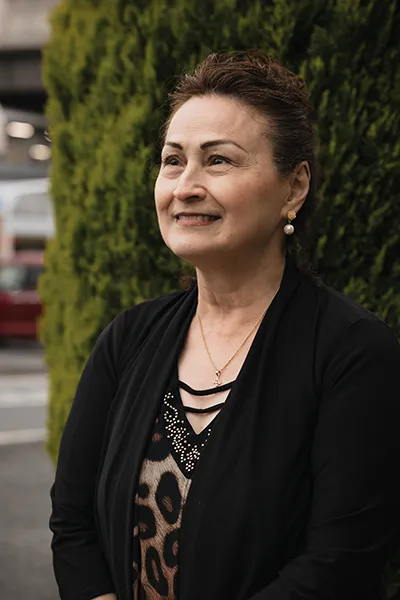 An Asian woman smiles while looking off into the distance.