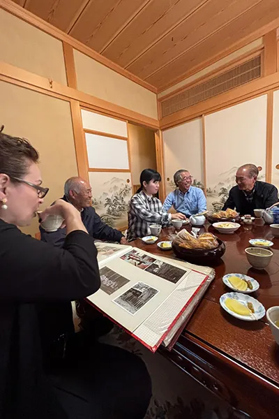 A group of people have tea while looking at photo albums.