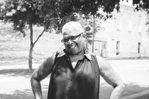 An African American woman smiles with hands on hips