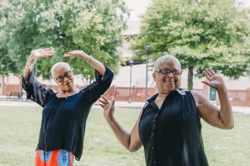 Two older African American women dance in a park