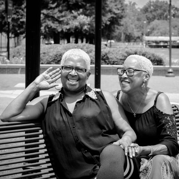 A black and white photo of two smiling women on a park bench