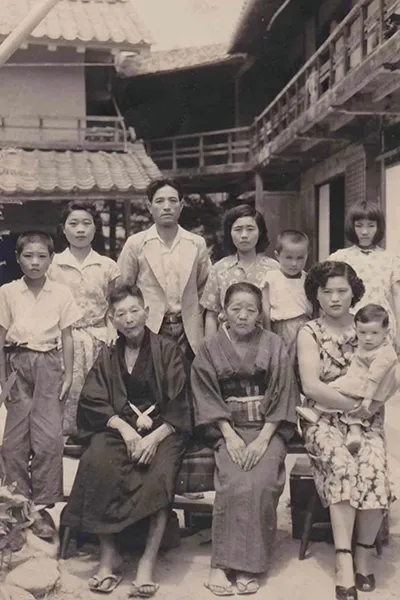 A group of Japanese people from different generations pose together in a vintage photograph.
