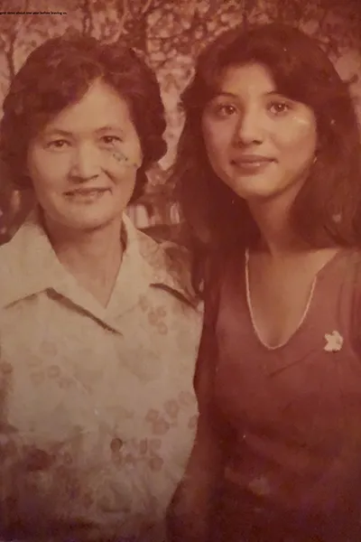 A mother and daughter stand together in a 1970s photograph.