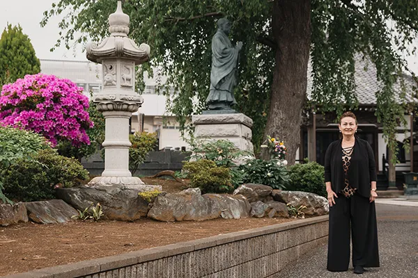 An Asian woman stands alone in a Japanese garden.