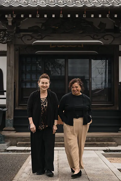 Two women walk together in front of a building in Japan.