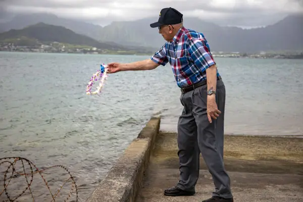 A man tosses a lei into the water