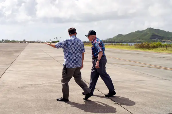 Two men walk across the tarmac at a military base