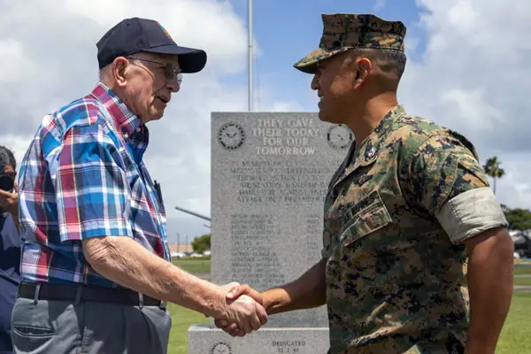 An older veteran and young soldier shake hands