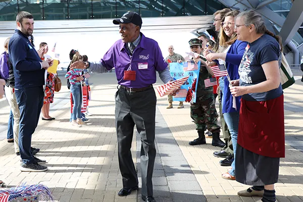 A smiling older African American man walking in front of a row of people