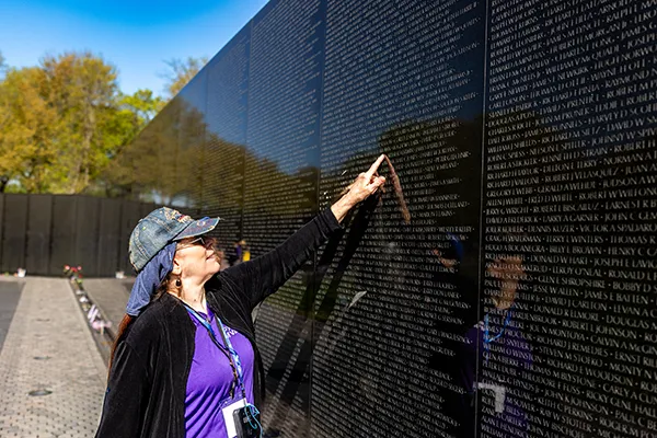 A woman points to a name on the Vietnam Veterans Memorial Wall.