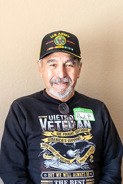 An older man in a black sweatshirt with military insignia.