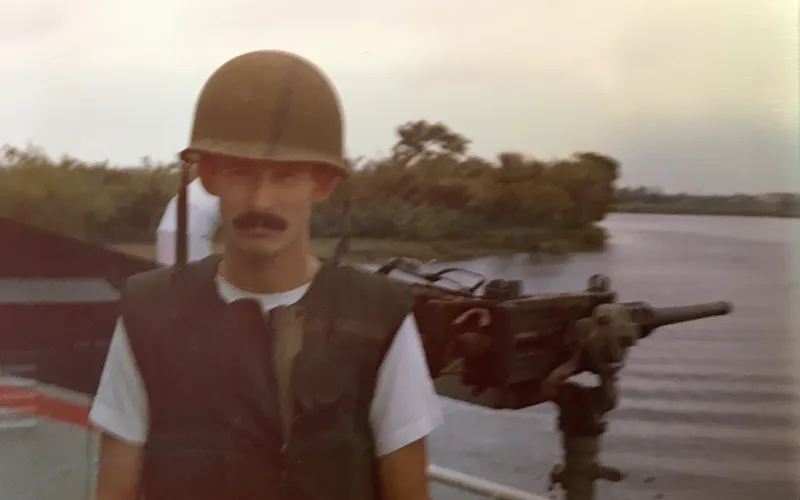 A Navy sailor from the Vietnam War stands by a river.