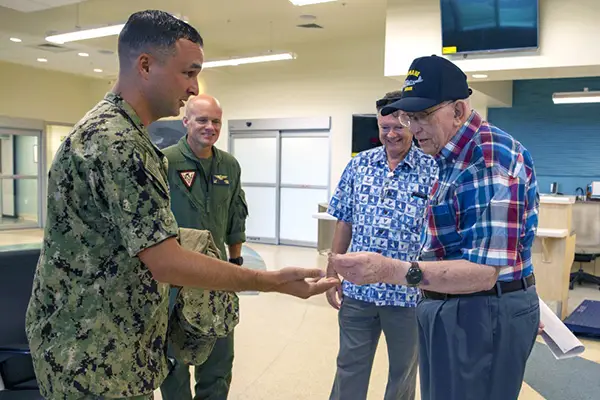 A young soldier handing a medal to an older veteran