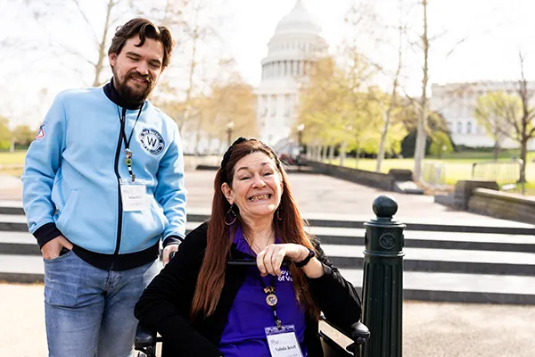 A man stands next to a woman in a wheelchair in front of the U.S. Capitol building in Washington, D.C.