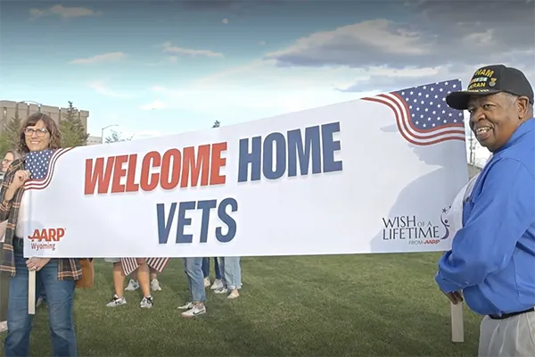 Two people hold a banner that reads “Welcome Home Vets.”