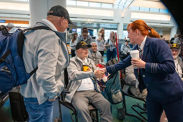 An older United States Army veteran stands arm in arm with his wife