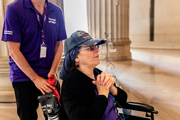 A woman in a wheelchair clasps her hands together.