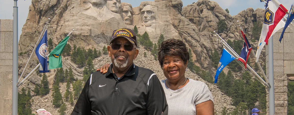 An older couple with Mt Rushmore in the background