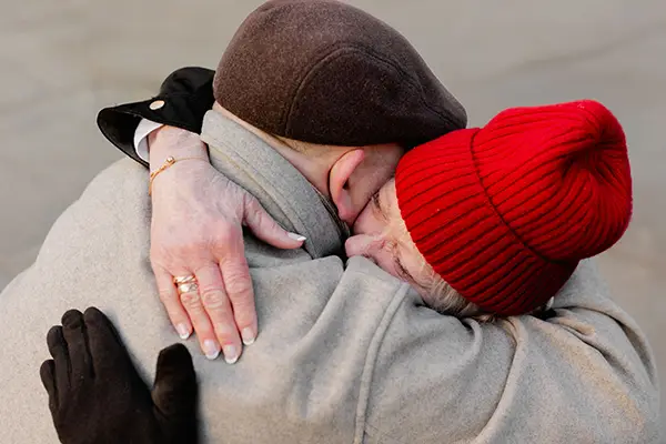 A man and woman wearing hats embrace.
