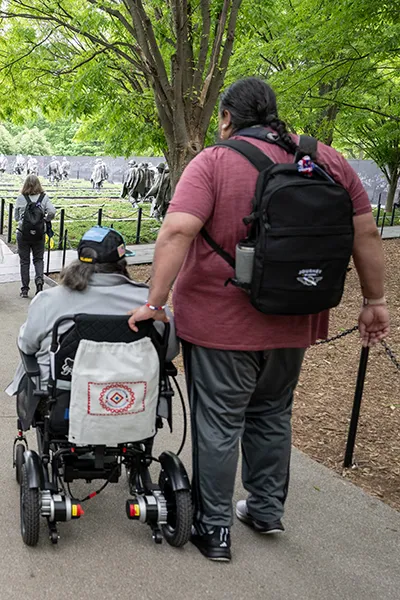 A man stands behind a woman in a wheelchair