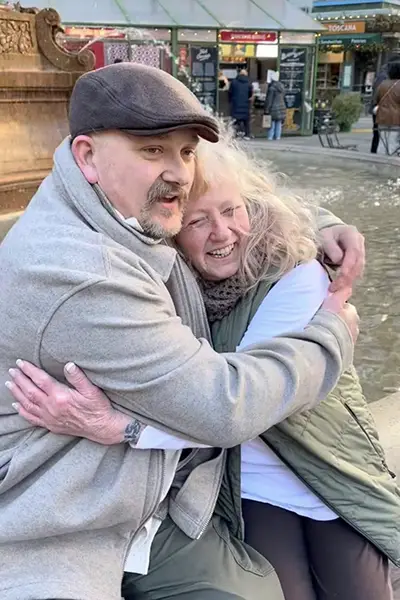 A man wraps his arms around an older woman.