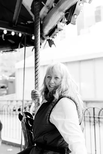 An older woman rides on a carousel.