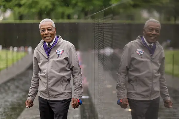 An African American man stands next to the Vietnam Veterans Memorial Wall.