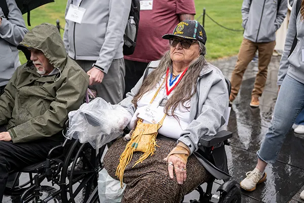 A woman Vietnam veteran sits in a wheelchair surrounded by people