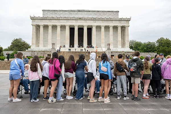 A group of teenagers stand in front of the Lincoln Memorial